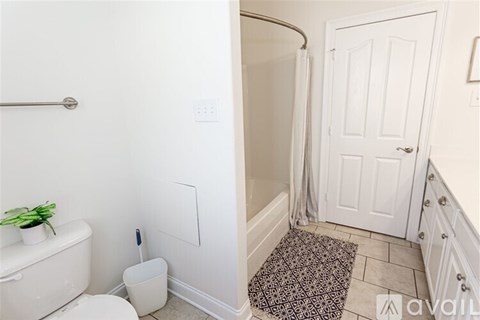 A bathroom with a toilet, a plant, and a shower.