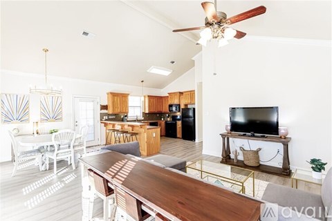 A modern open plan living and dining area with a television and a kitchen in the background.