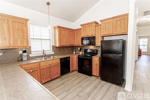 A kitchen with wooden cabinets and a black refrigerator.