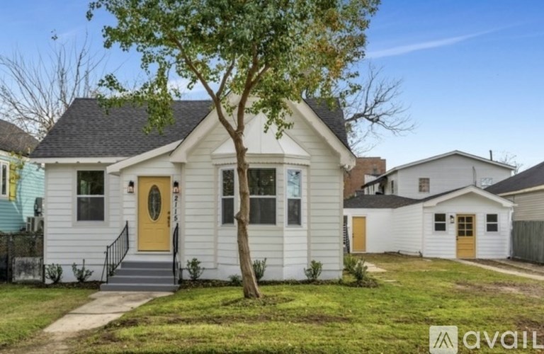A small white house with a yellow door is for sale.