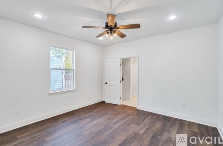 A room with a ceiling fan and wooden flooring.