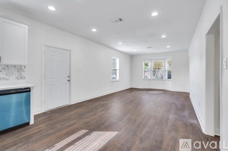 A spacious room with wooden flooring and white walls.