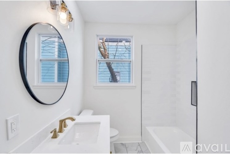 A bathroom with a white sink and a round mirror.