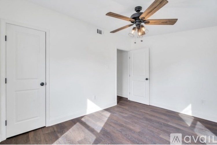 A room with a ceiling fan and wooden flooring.