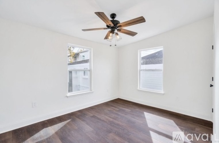 A room with a ceiling fan and two windows.
