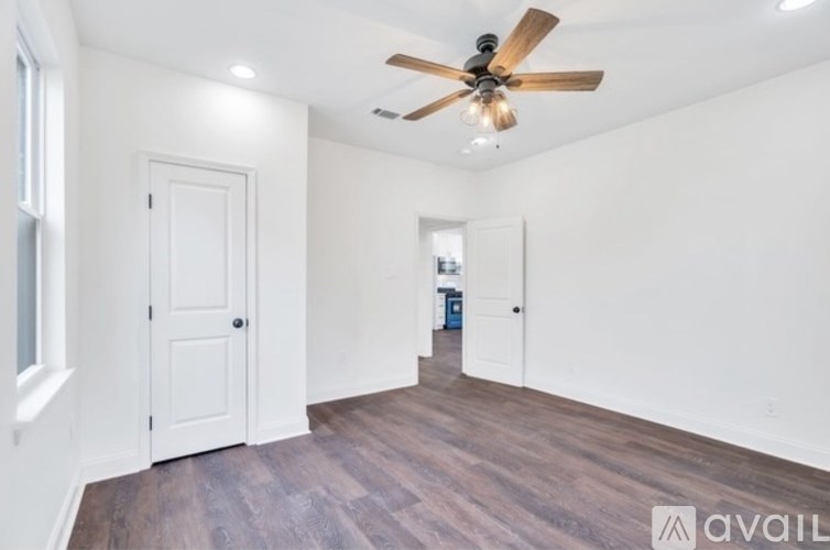 A room with a ceiling fan and wooden flooring.