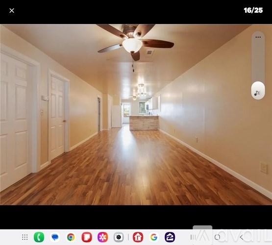 A long hallway with a ceiling fan and wooden floors.