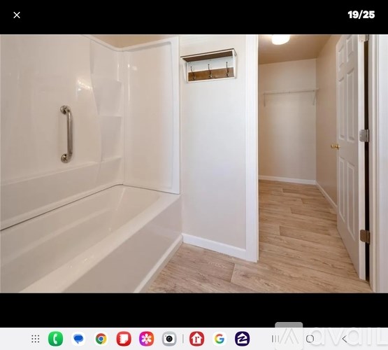 A white bathroom with a tub and a towel rack.