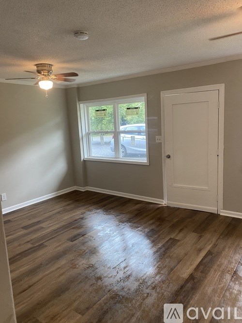 A room with a ceiling fan and a window with a view of a street.