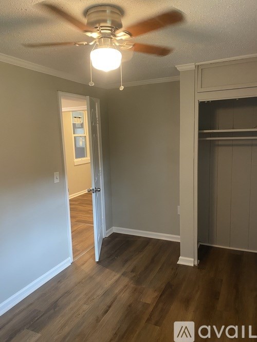 A room with a ceiling fan and a door leading to another room.