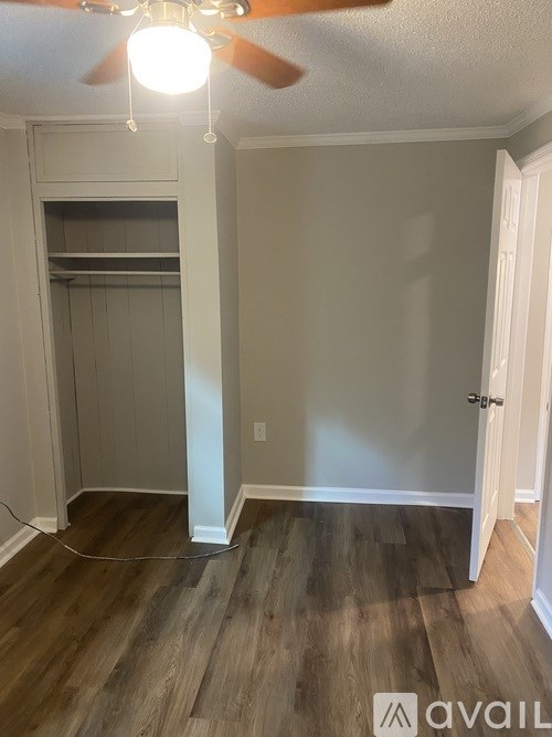 A room with a ceiling fan and wooden flooring.