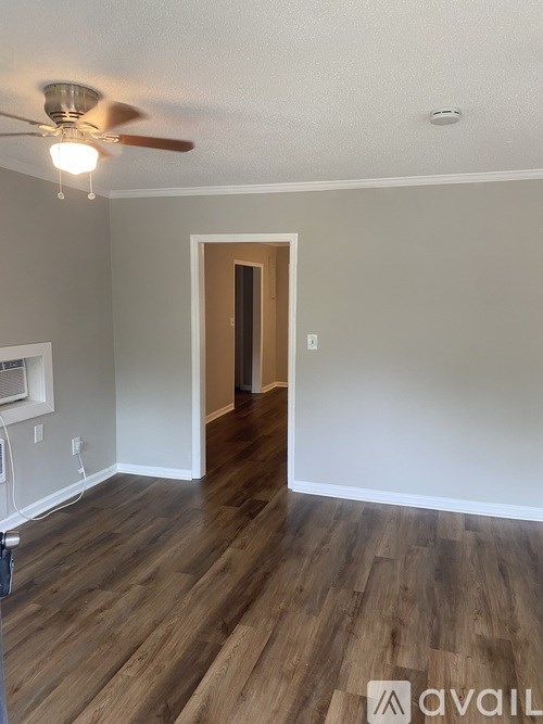 A room with a ceiling fan and wooden flooring.