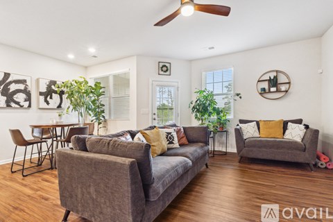 A living room with a grey couch and a ceiling fan.