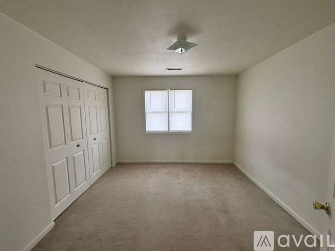 A room with a white door, a window, and a ceiling fan.