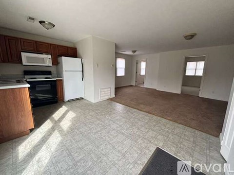 A kitchen with a white refrigerator and microwave, and a tiled floor.