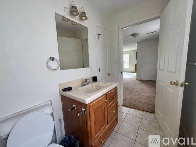 A bathroom with a toilet, sink, and mirror.