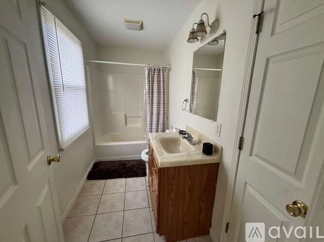 A small bathroom with a sink, mirror, and shower.