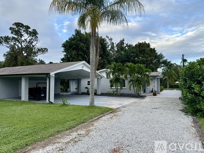 A house with a gravel driveway and a palm tree in front.