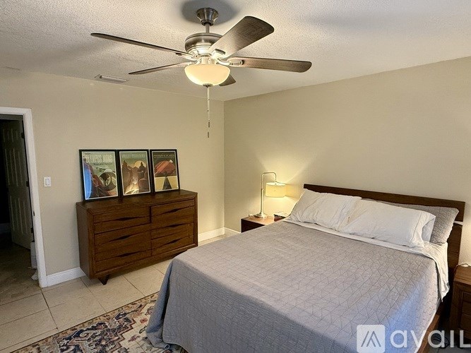 A bedroom with a bed, dresser, and ceiling fan.