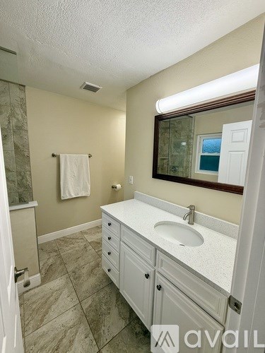 A bathroom with a sink, mirror, and tiled floor.