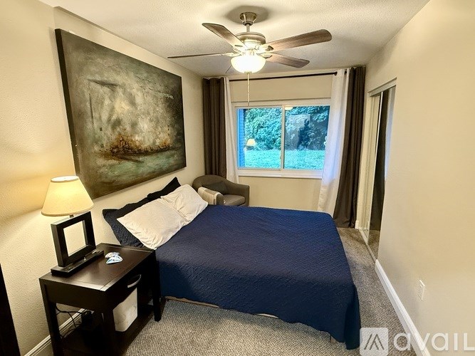 A bedroom with a bed, nightstand, and a painting on the wall.