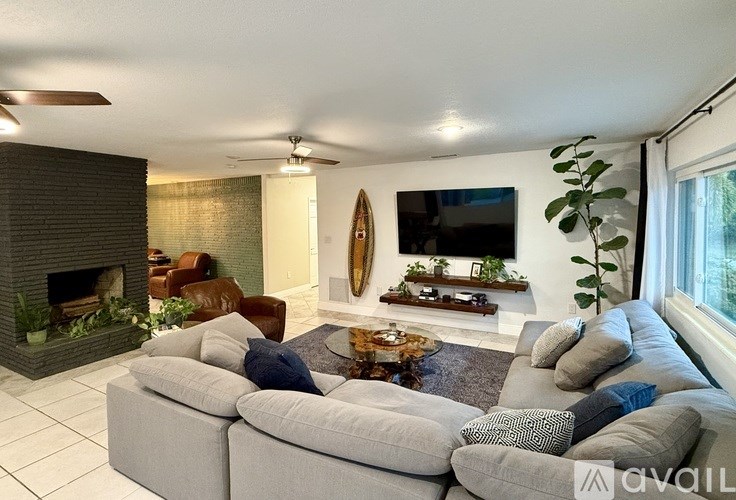 A living room with a grey sectional sofa and a fireplace.