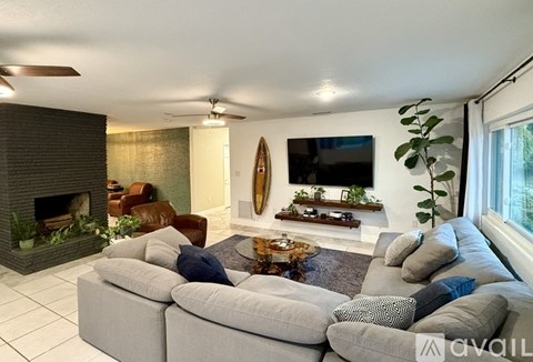 A living room with a grey sectional sofa and a fireplace.