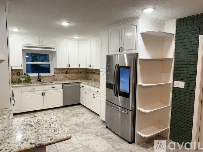 A kitchen with a granite countertop and a refrigerator with a water dispenser.