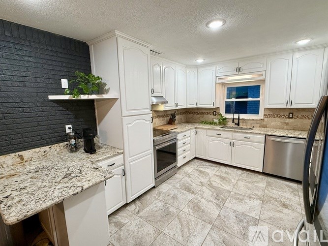 A kitchen with white cabinets and a granite countertop.