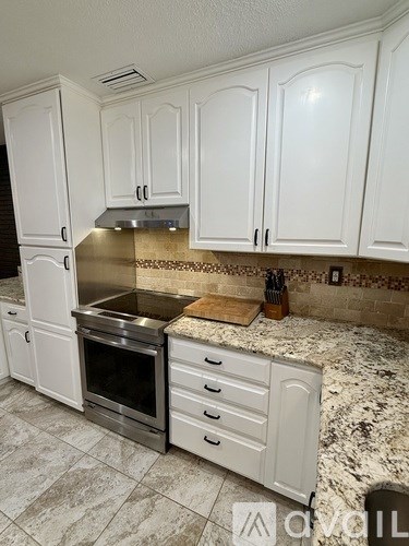 A kitchen with white cabinets and a marble countertop.