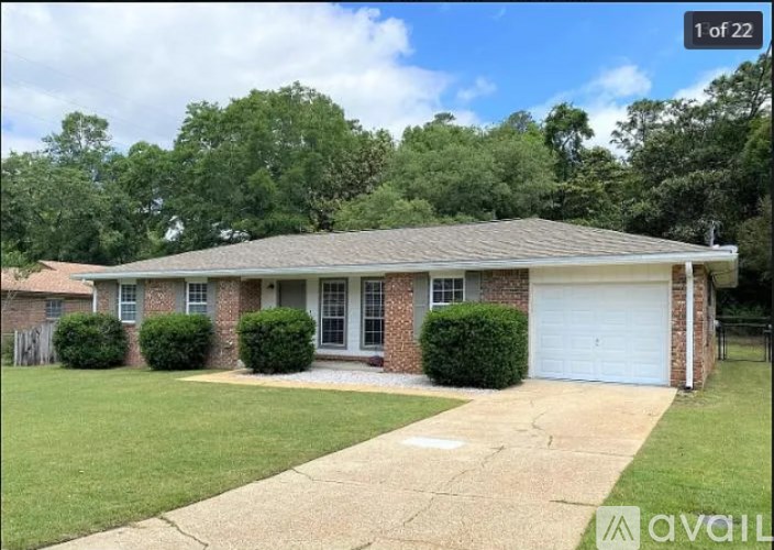 A house with a white garage door is surrounded by greenery.