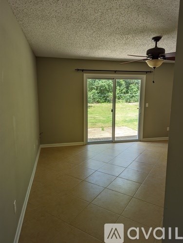 A room with a ceiling fan and sliding glass doors leading to a backyard.