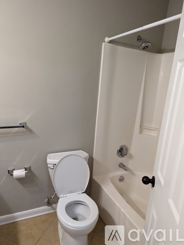 A white toilet is in a bathroom with a white shower.