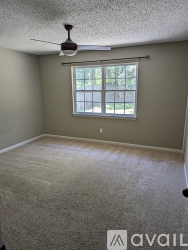 A room with a carpeted floor and a ceiling fan.