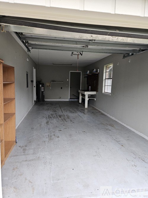 A large empty room with a wooden shelf on the left side.