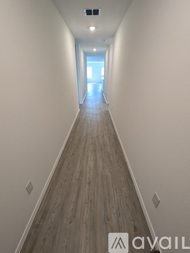 A long hallway with wood flooring and white walls.