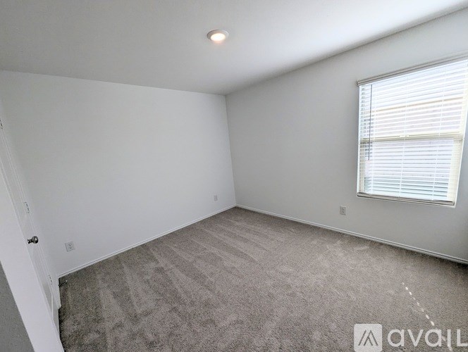 A room with a carpeted floor and a window with blinds.