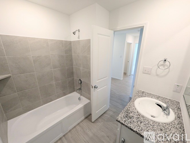 A bathroom with a white tub, sink, and tiled walls.