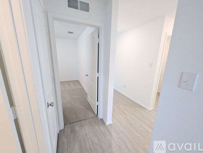 A hallway with a door on the left and a wall on the right.