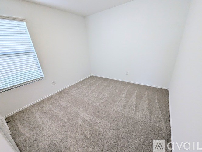 A room with a carpeted floor and a window with blinds.