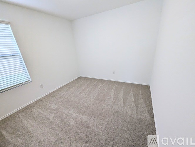 A room with a carpeted floor and a window with blinds.