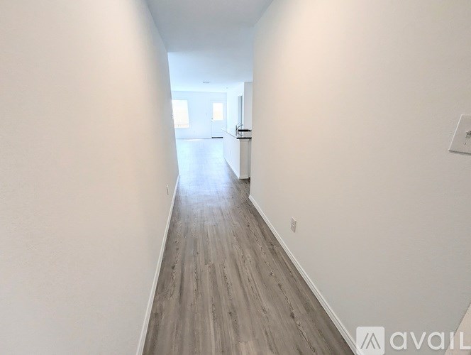 A long hallway with wood flooring and white walls.