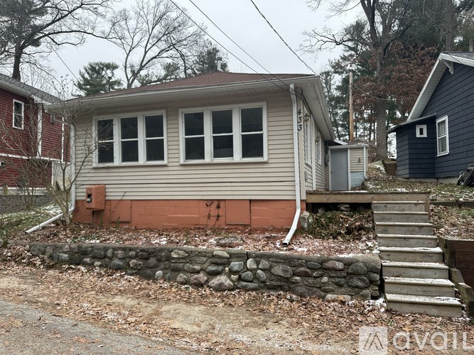 A house with a grey siding and a stone wall in front.