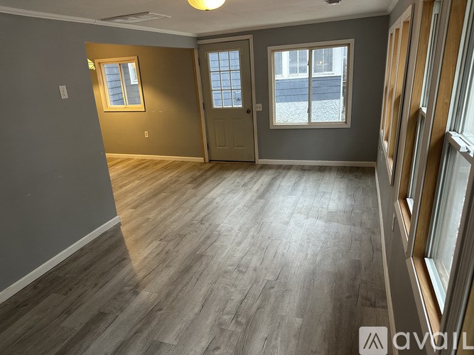 A room with wooden flooring and a window with a view of a street.