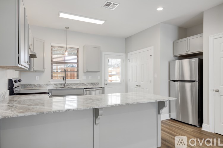 A modern kitchen with white cabinets and a marble countertop.