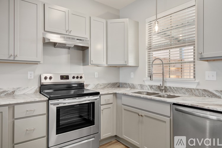 A kitchen with a stove, sink, and cabinets.
