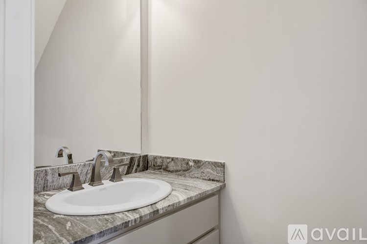 A bathroom sink with a marble countertop and a mirror above it.