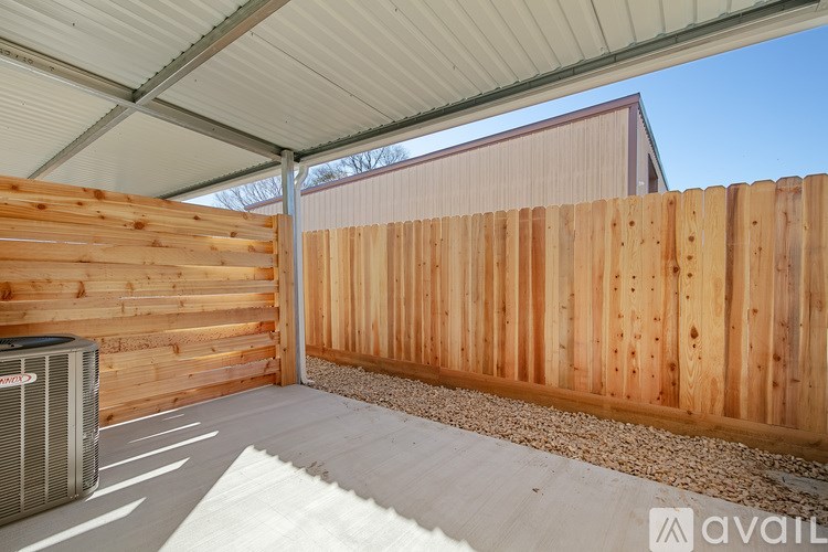 A patio area with a wooden fence and a wall-mounted air conditioning unit.