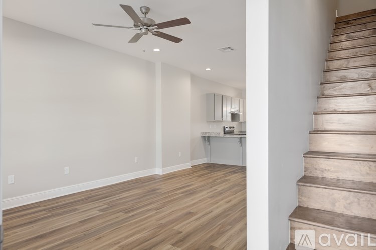 A room with a ceiling fan and wooden flooring.
