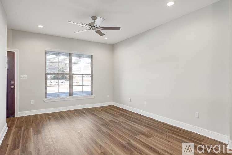 A spacious room with a ceiling fan and wooden flooring.